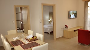 A hotel room with a dining area, a bed, a TV, and a bathroom. - Daniel Luxury Apartments (Rhodes)