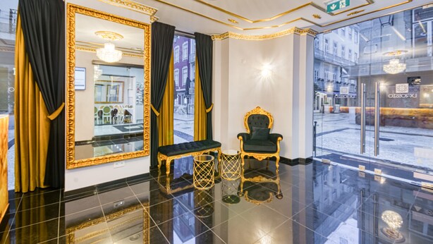 A luxurious lobby with a large mirror, a plush chair, a bench, and a chandelier. - Hotel LX Rossio (Lisbon)