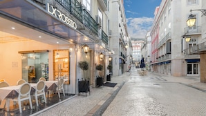A hotel with a glass facade, outdoor seating, and a cobblestone street. - Hotel LX Rossio (Lisbon)