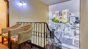A room with a view of a cityscape through a large window, a staircase, and two wicker chairs with colorful cushions. - Hotel LX Rossio (Lisbon)