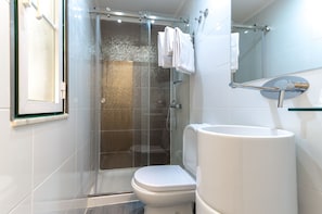 Un bagno moderno con doccia vetrata, un water bianco e un lavandino grande.