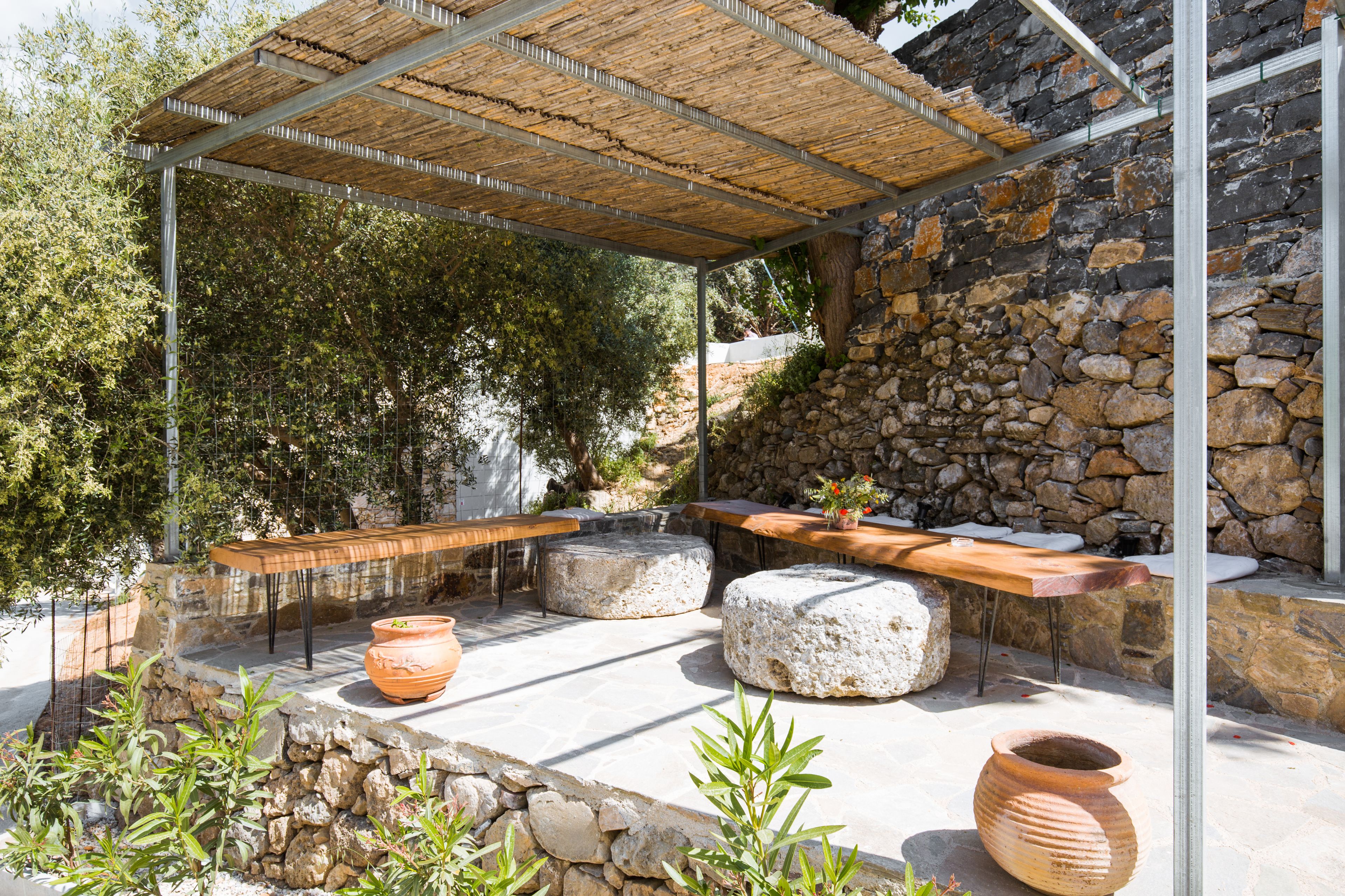 Un espace extérieur aménagé en terrasse, avec des murs en pierre, des meubles en bois et des plantes en pot.
