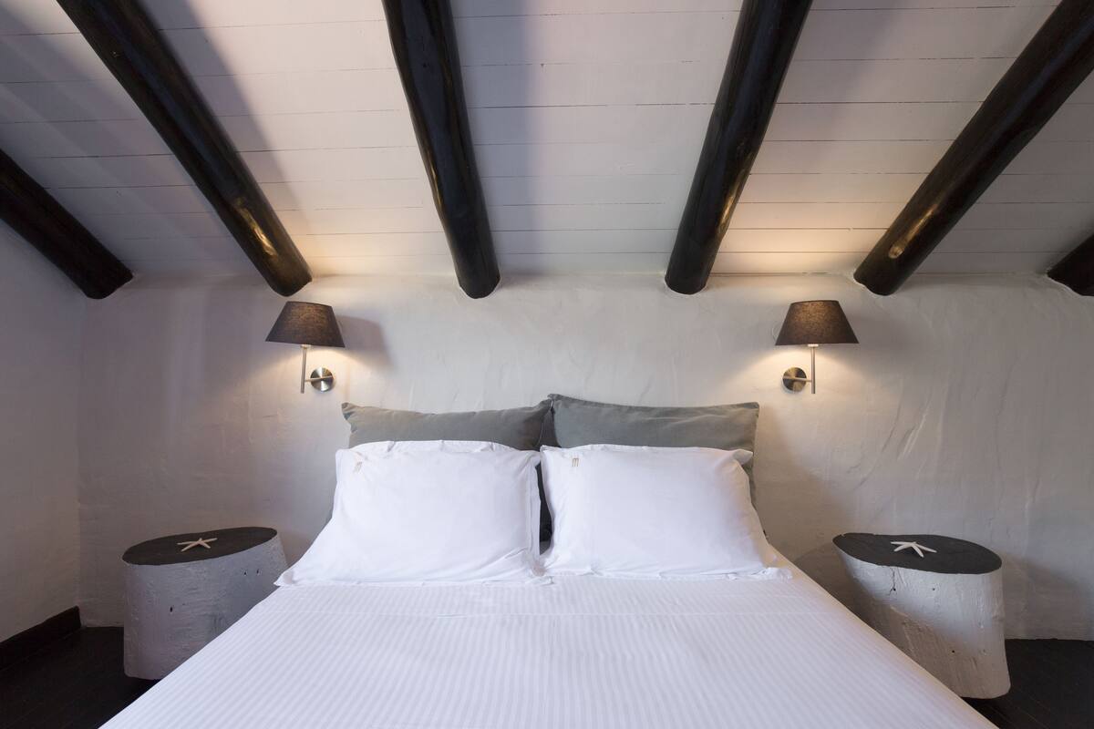 Een slaapkamer met een bed, twee bedlampen en een rond nachtkastje met een ster decoratie.