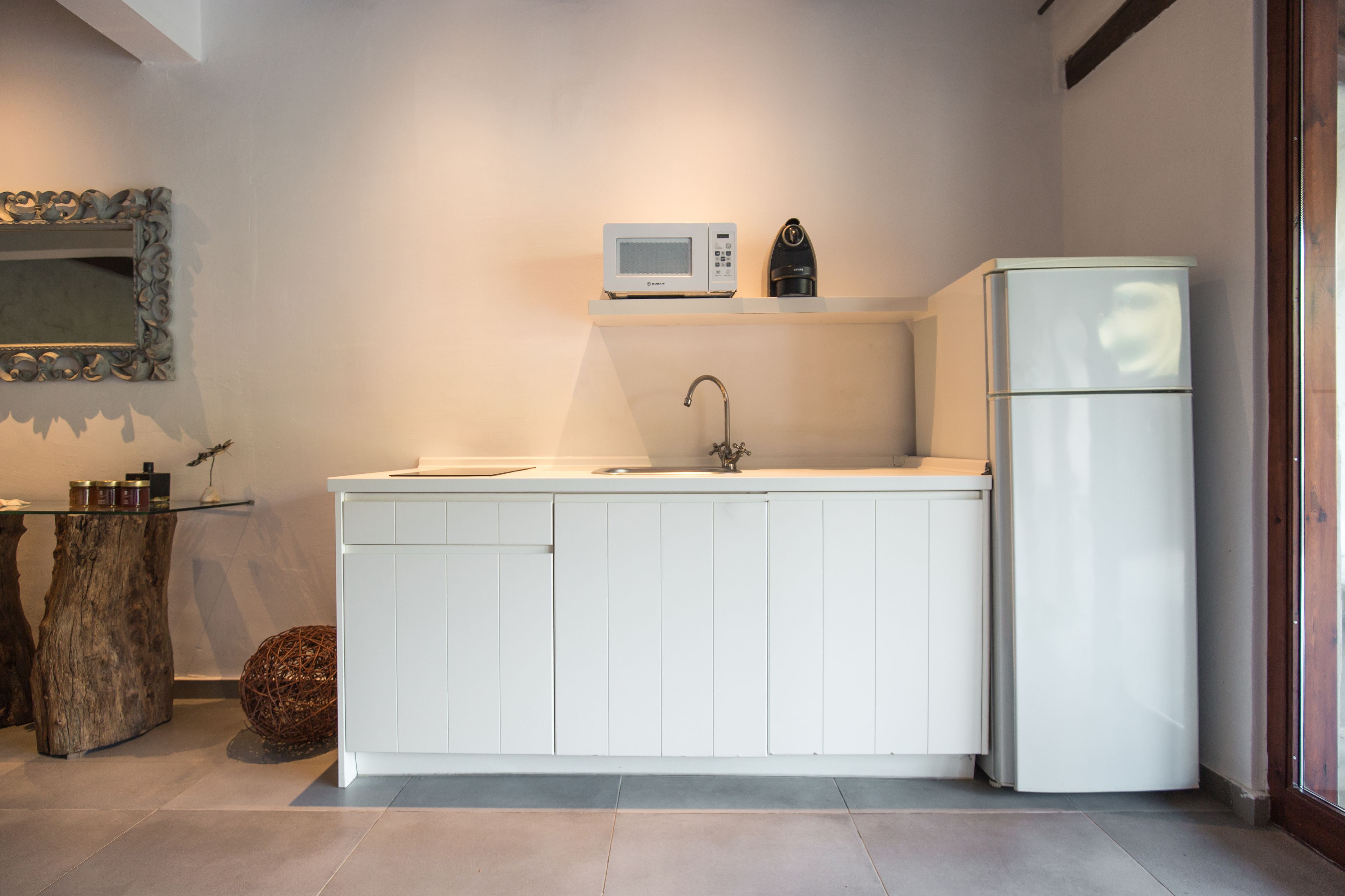 A modern kitchen with white cabinetry, a microwave, a coffee maker, and a refrigerator.