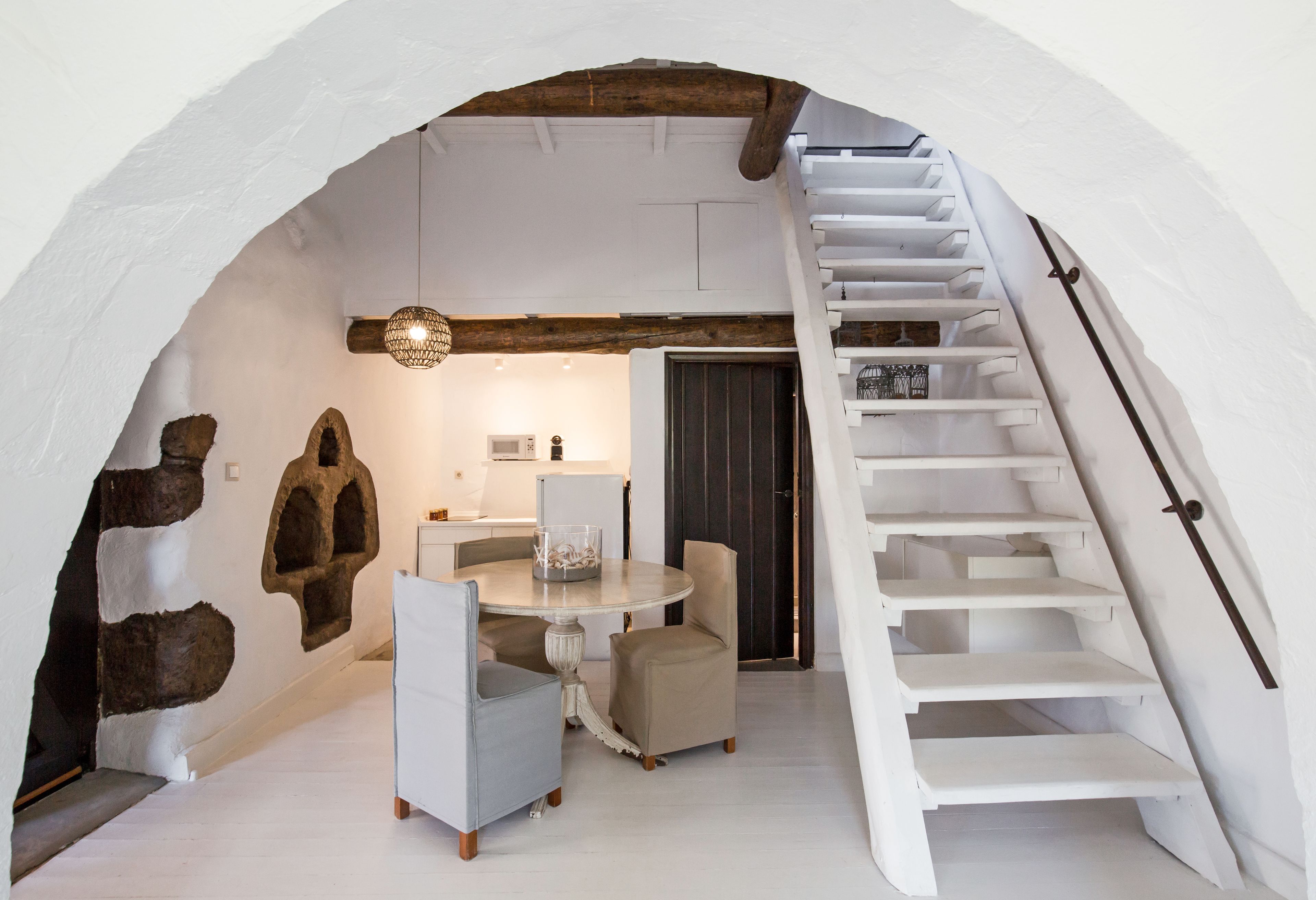 A dining area with a round table and chairs, a staircase, and stone wall decorations.