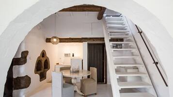 A dining area with a round table and chairs, a staircase, and stone wall decorations.