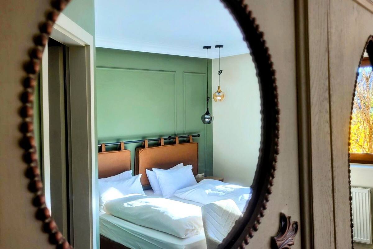Ein Schlafzimmer mit Bett, Kopfteil und hängenden Pendelleuchten.