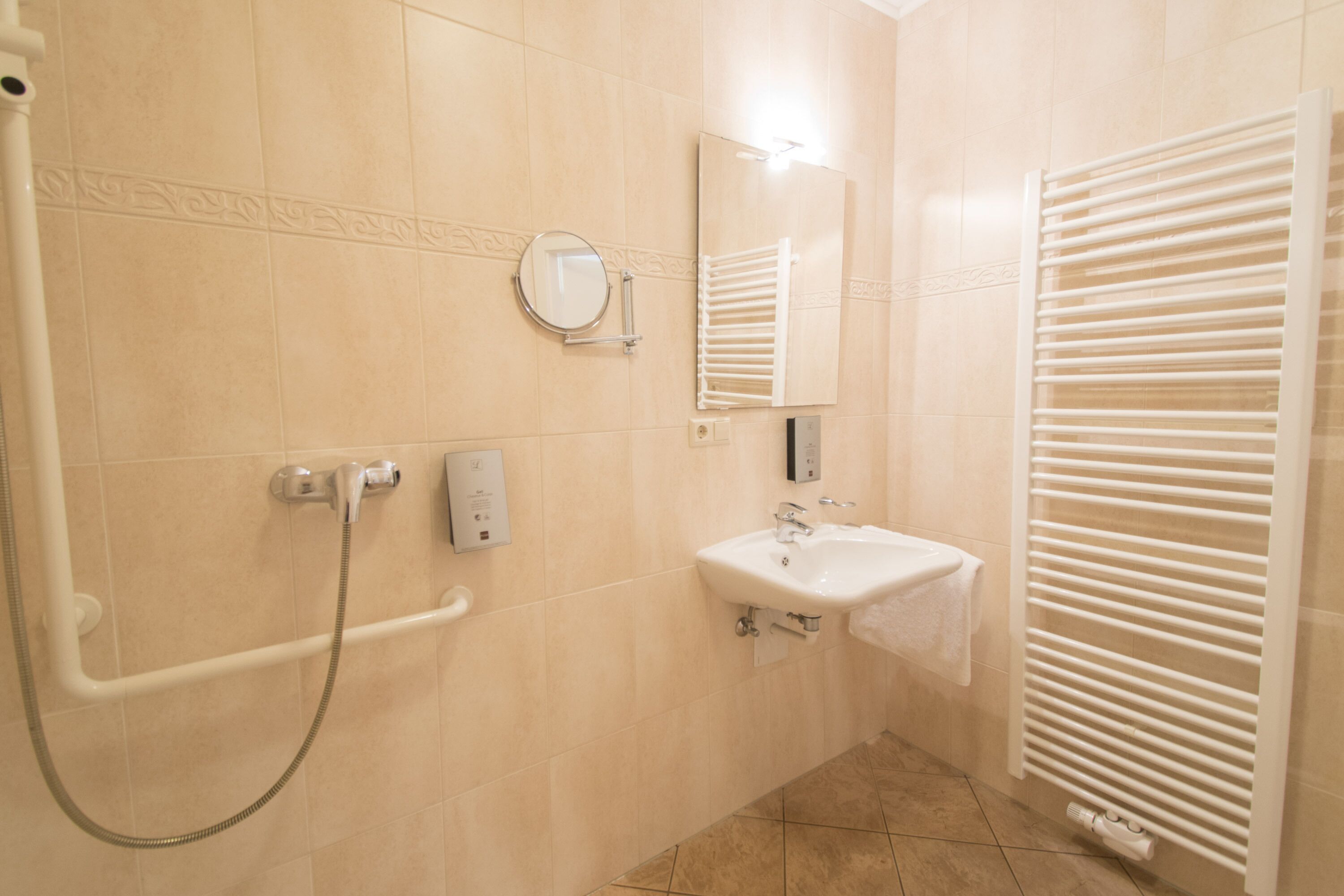 A bathroom with a shower, sink, and towel rack.