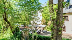 Une cour dotée d’un espace extérieur aménagé pour s’asseoir, entourée d’arbres et bordée d’un bâtiment sur lequel on peut voir une enseigne.