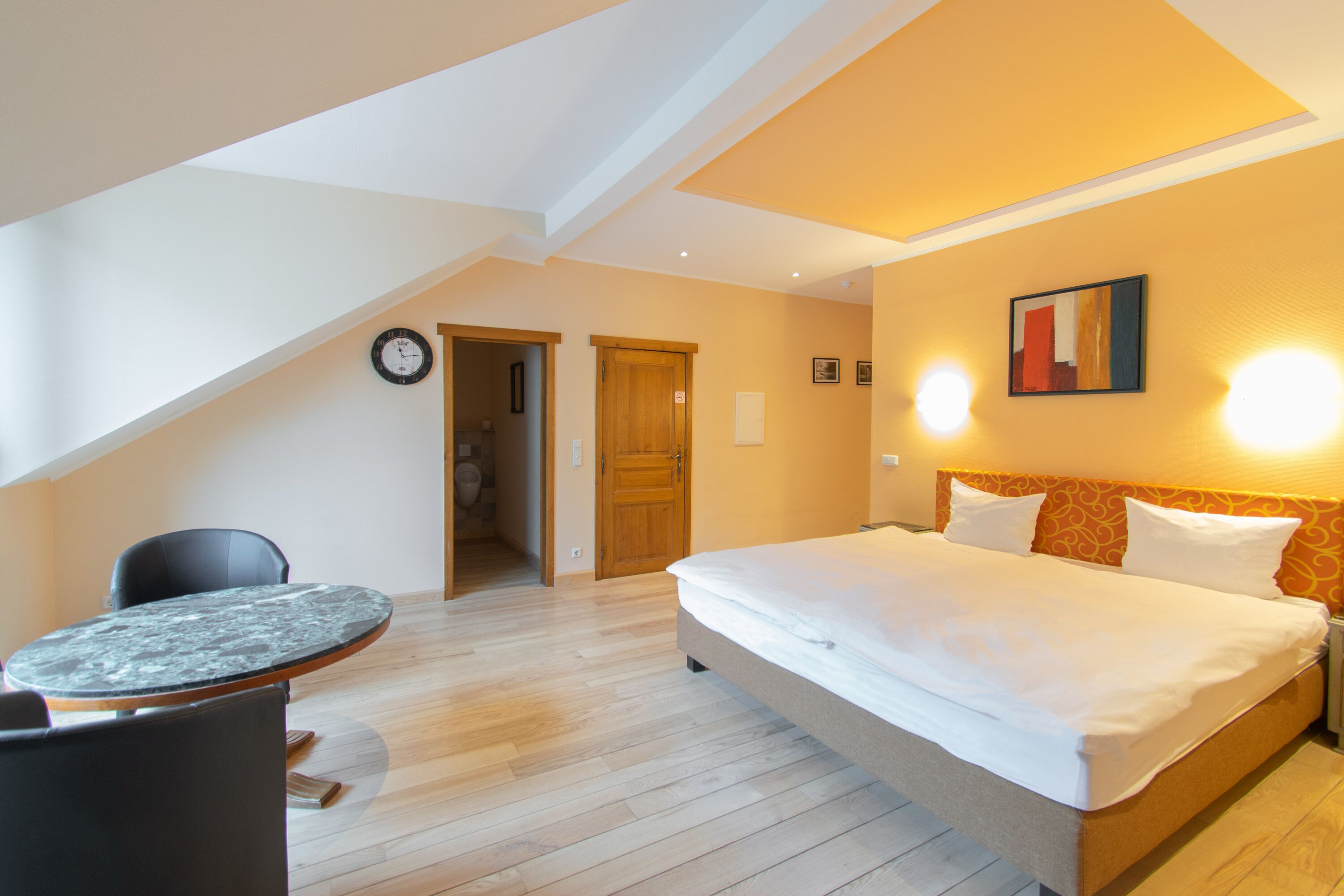 A bedroom with a bed, a round table, and a chair.