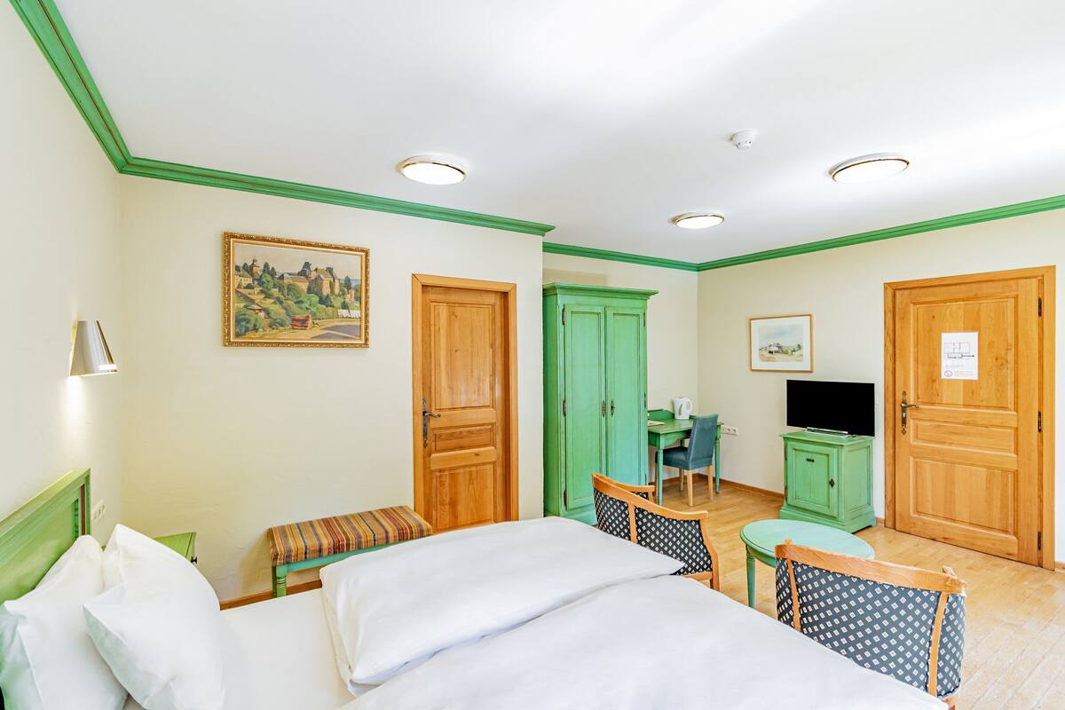 Ein Hotelzimmer mit einem Bett, einem Schreibtisch, einem Fernseher und einem grünen Schrank.