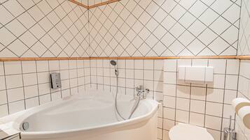 A modern bathroom with a freestanding bathtub, a toilet, and a showerhead.