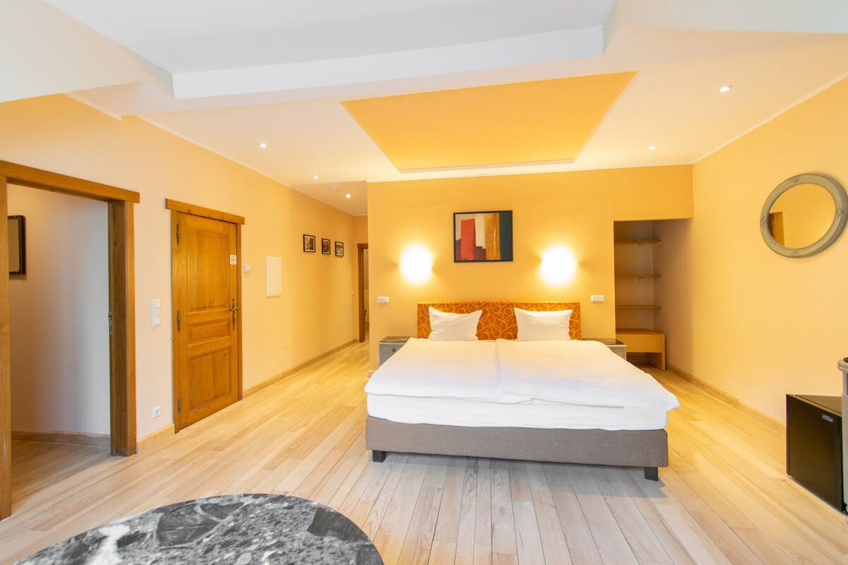 Ein modernes Schlafzimmer mit einem großen Bett, Holztüren und einem runden Spiegel an der Wand.