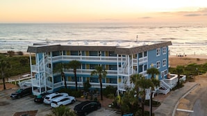 A multi-story hotel with a rooftop pool, located near a beach with a view of the ocean.