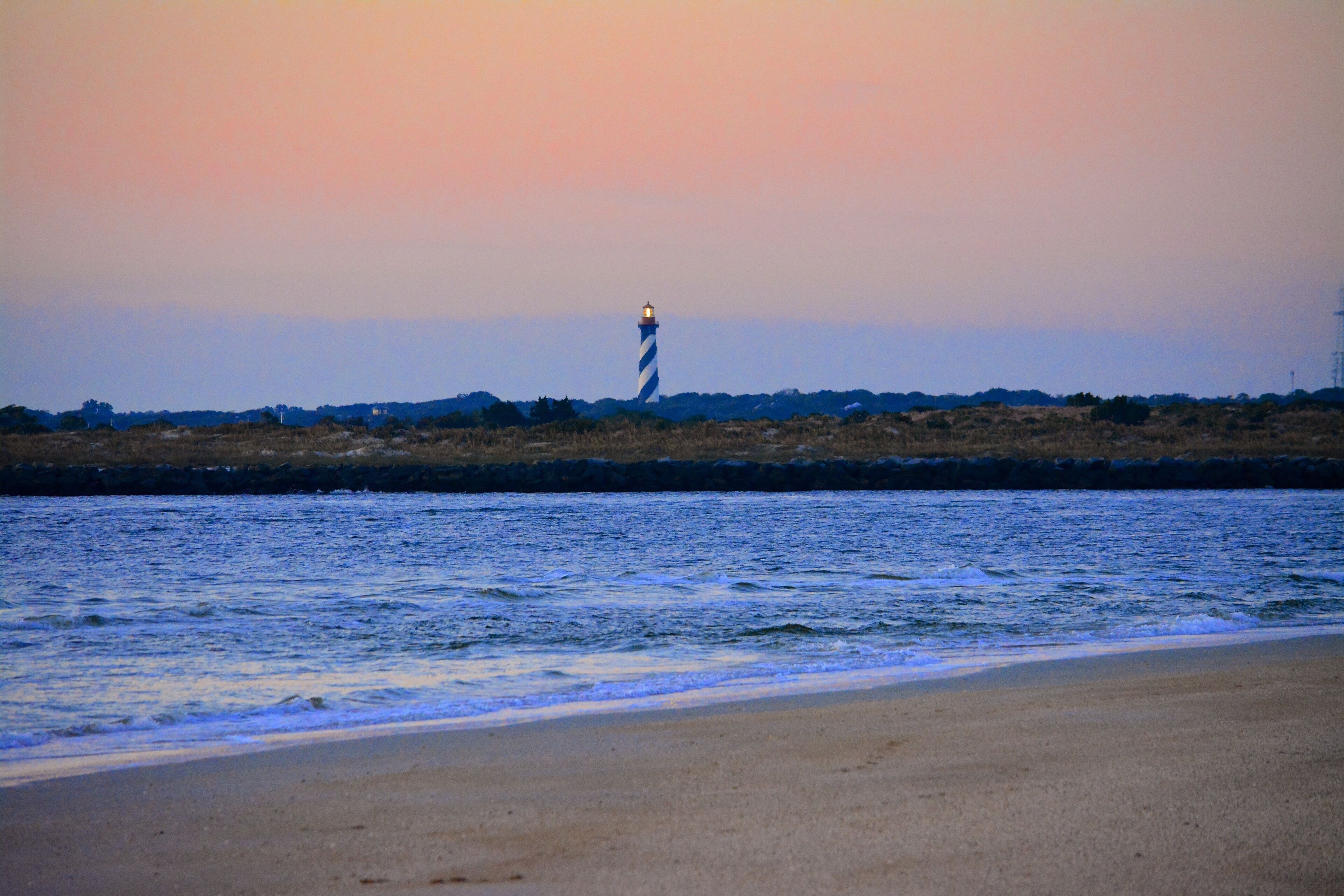 A beach with a lighthouse in the distance.