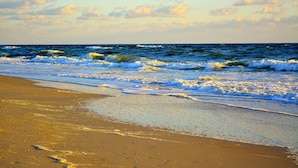 A beach with waves and a clear sky.