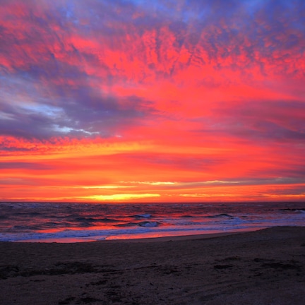A beach with a sunset and ocean waves.