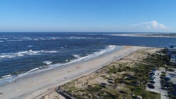 A beach with a wooden walkway, a parking area, and a view of the ocean.