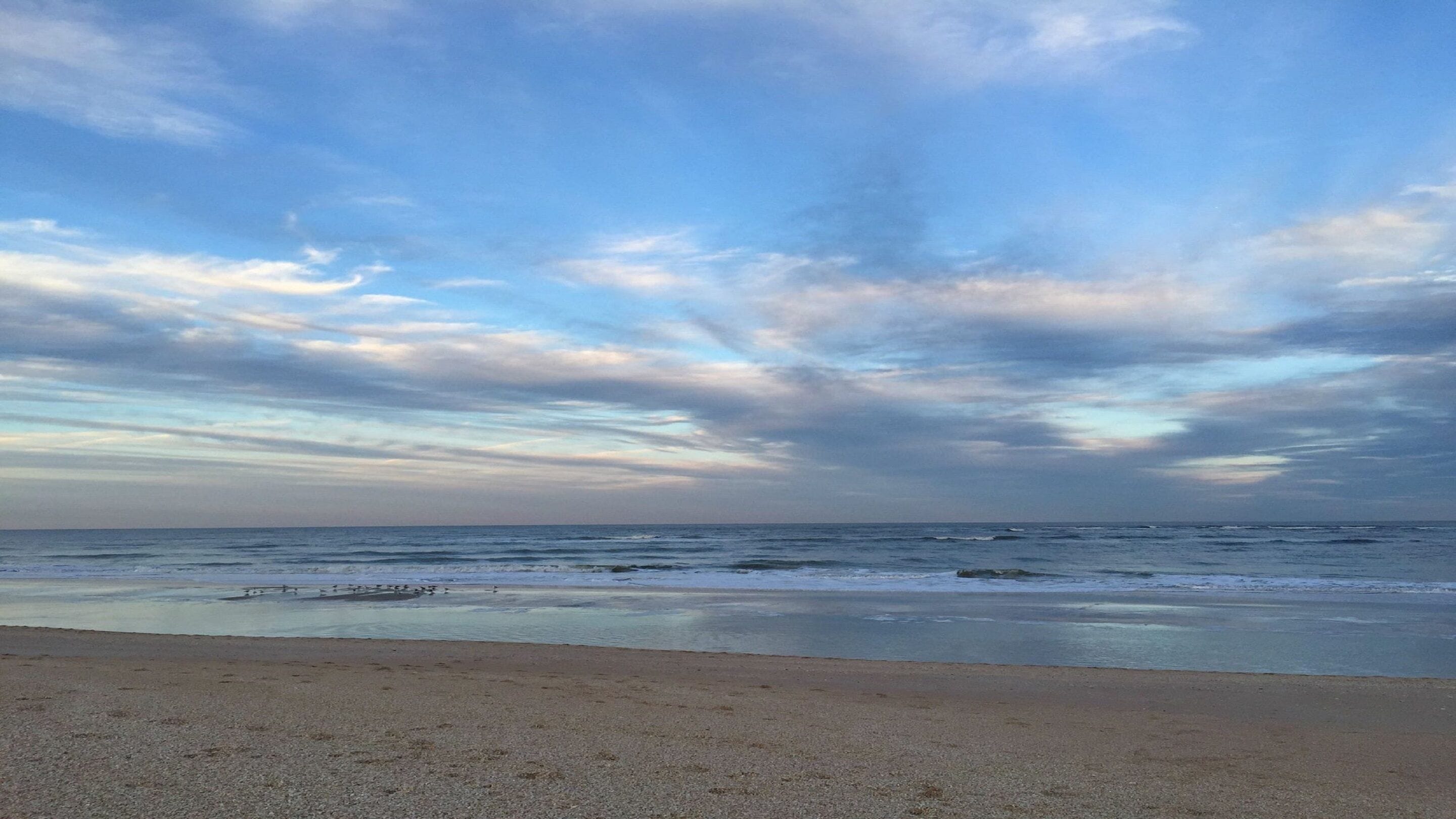 Une plage au rivage de galets, offrant une vue sur l’océan sous un ciel nuageux.