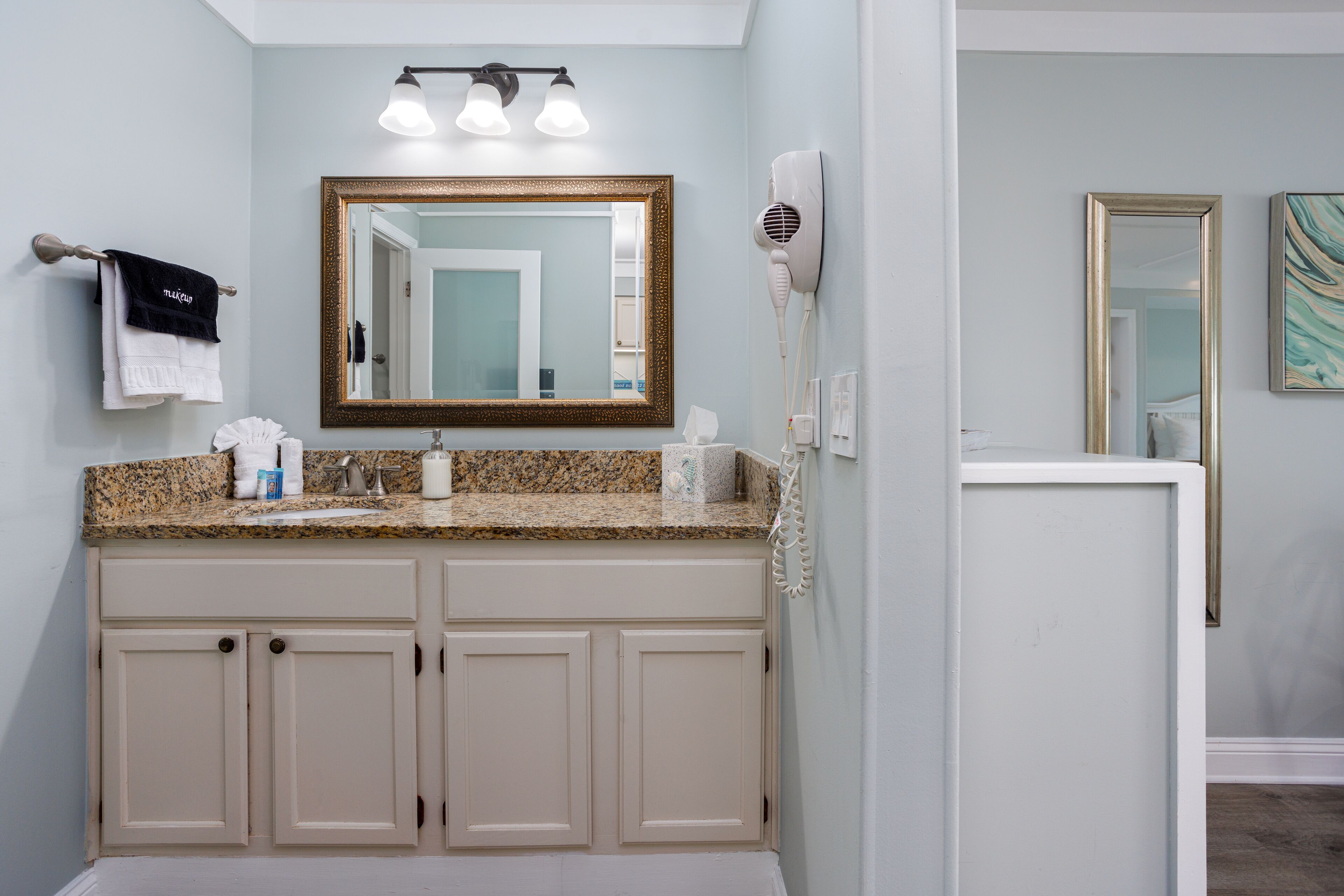 A bathroom with a double vanity, a large mirror, a hairdryer, and a towel rack.