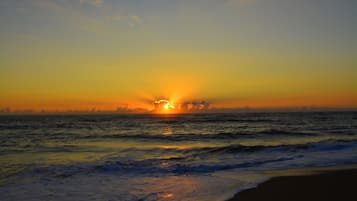 Un coucher de soleil sur l’océan, avec des vagues qui se rapprochent du rivage.