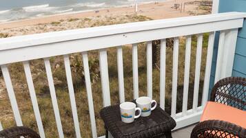 A balcony with wicker furniture, a table, and two mugs.
