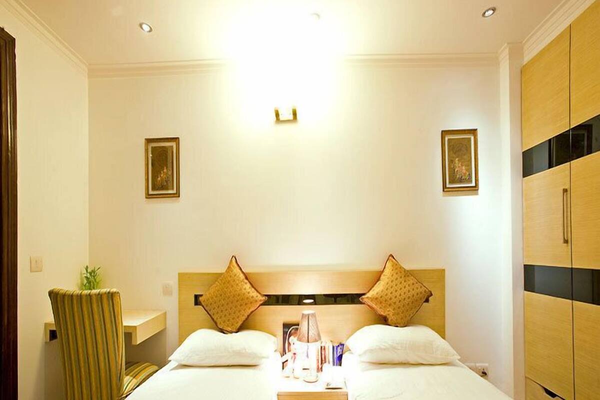 A hotel room with two beds, a desk, and a wardrobe.
