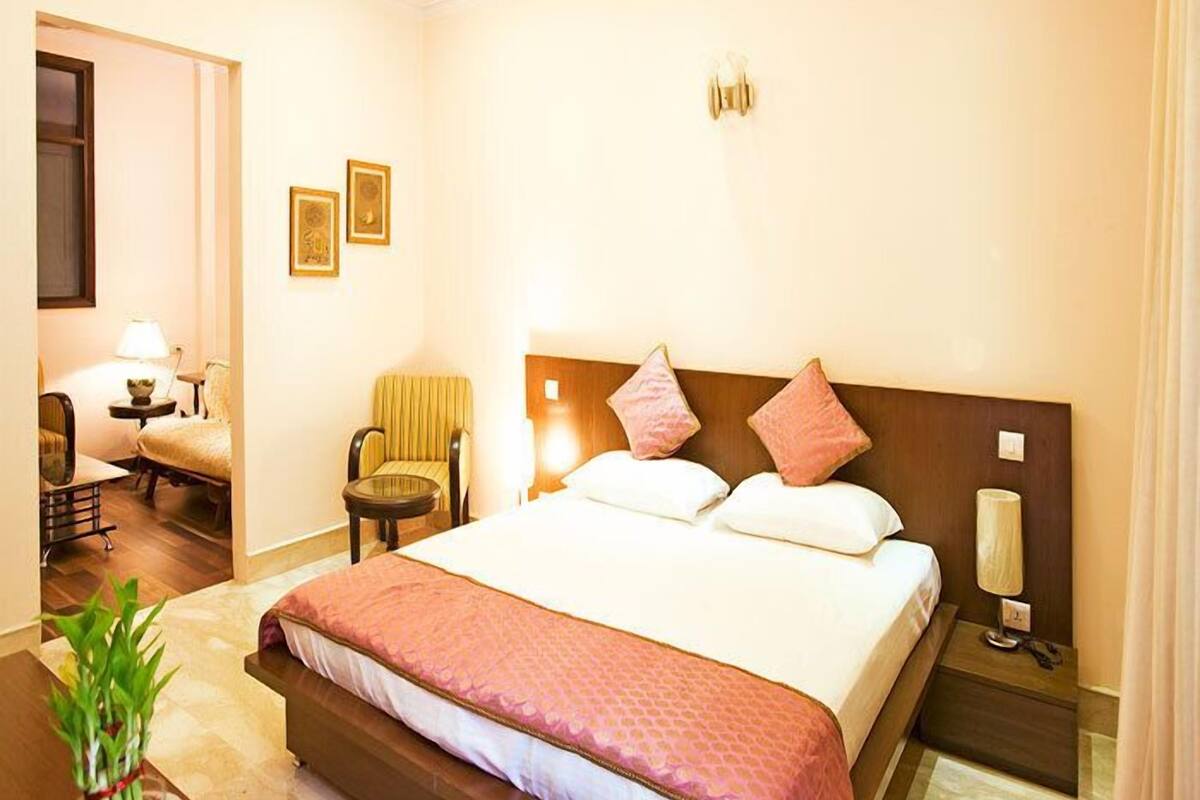 A hotel room with a bed, bedside tables, a chair, a lamp, and a plant.