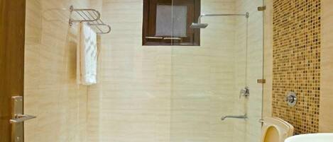 A modern bathroom with a glass shower enclosure, a small window, and a vanity with a sink.