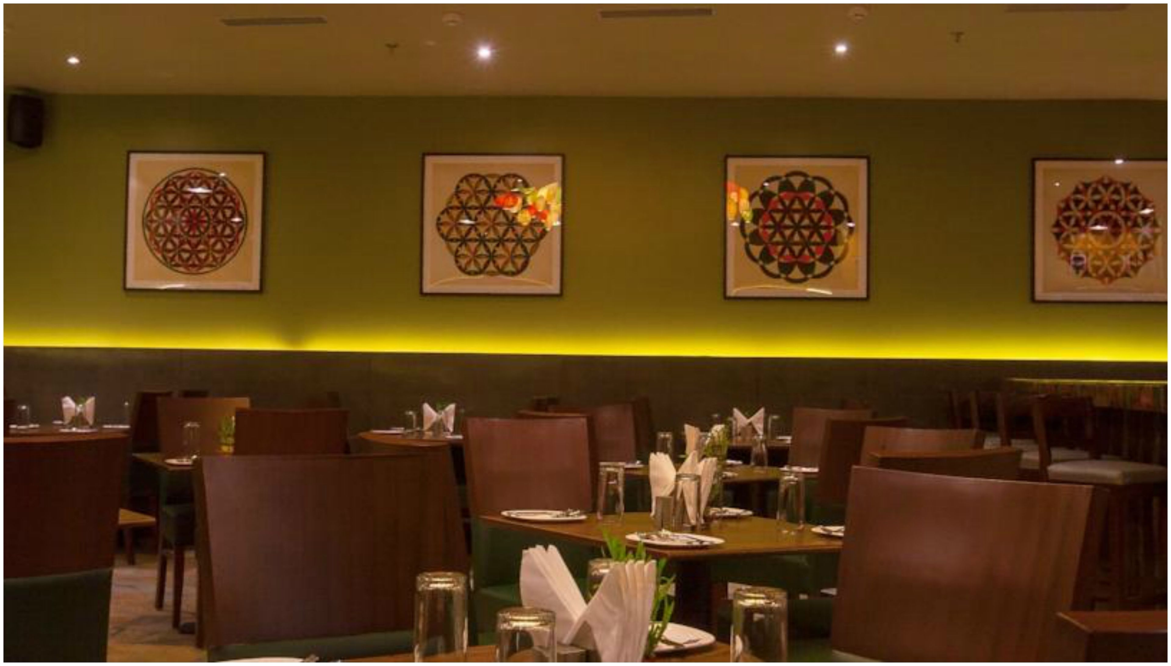 A restaurant with tables set for dining, chairs, and framed wall art.