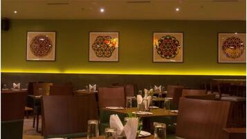 A restaurant with tables set for dining, chairs, and framed wall art.