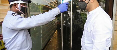 A security officer checking a person's ID at a building entrance.