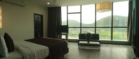 Une chambre d’hôtel avec un grand lit, un bureau, une chaise, une télévision et une vue sur l’extérieur.