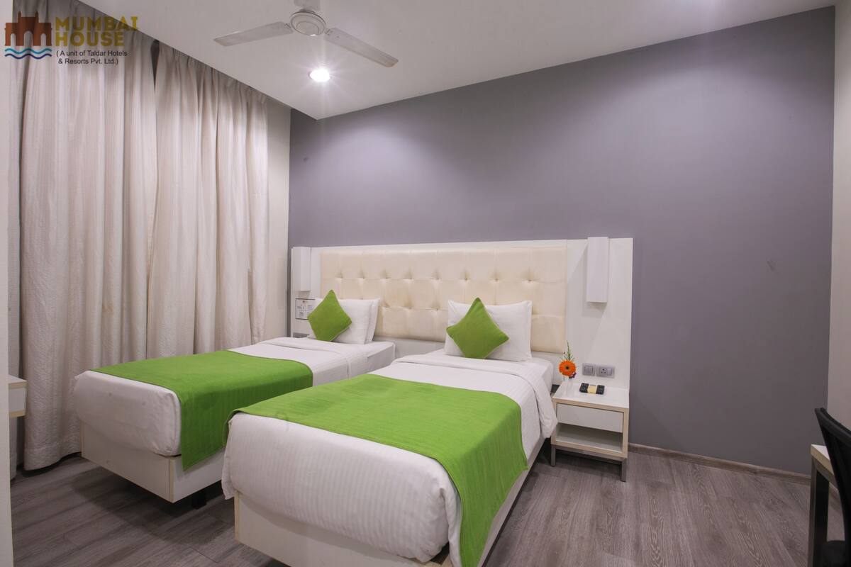 Ein Hotelzimmer mit zwei Betten, einem Nachttisch, einer Lampe und einem Deckenventilator.