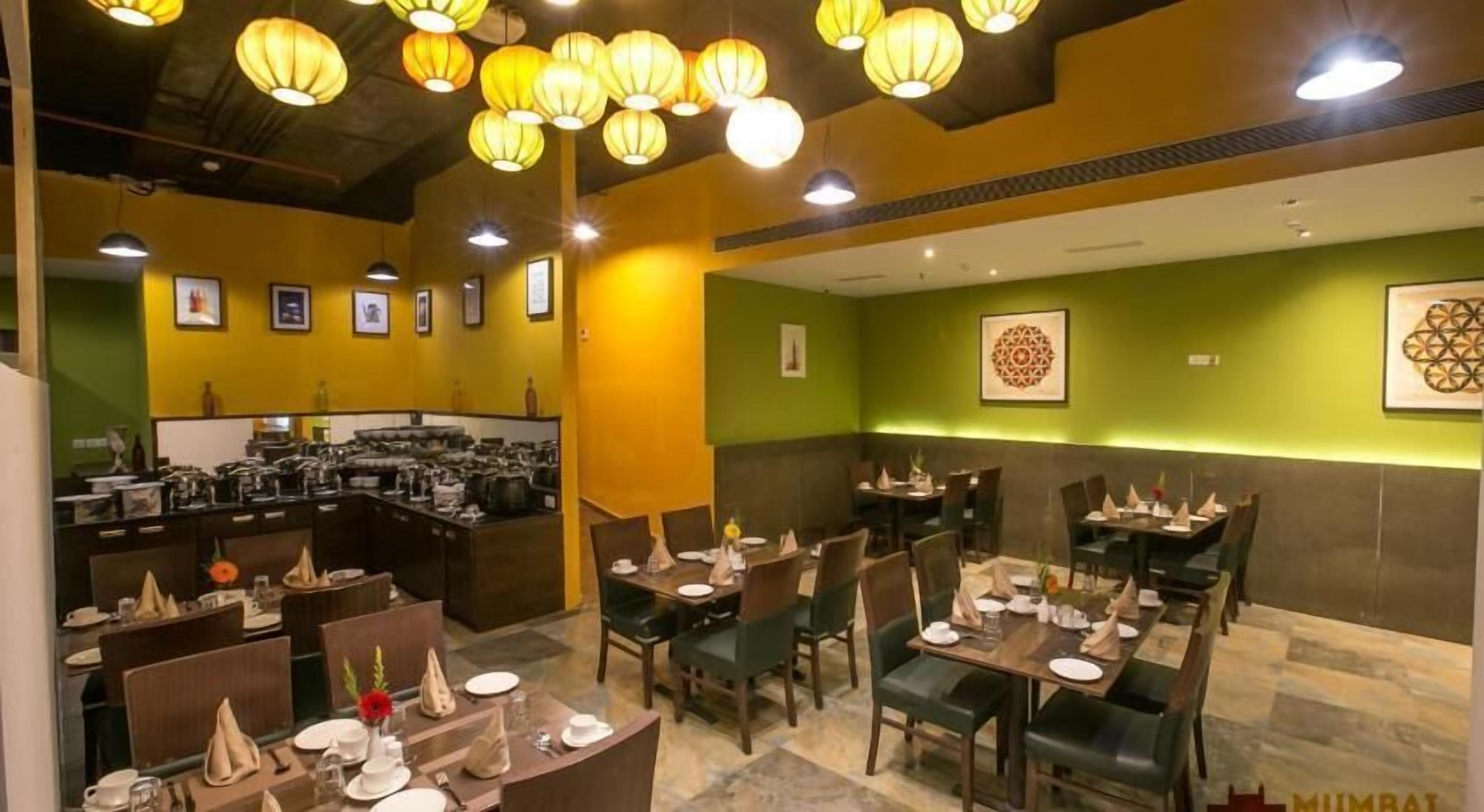 Un ristorante con diversi tavoli, sedie e una zona cucina visibile sullo sfondo.