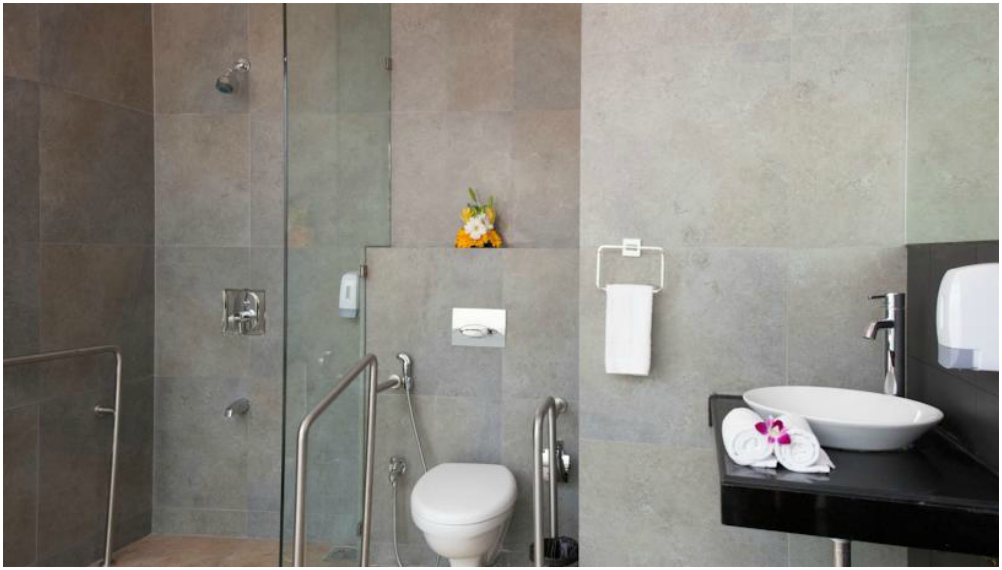 A modern bathroom with a glass shower enclosure, a toilet, a sink, and a towel rack.
