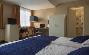 A hotel room with a bed, a desk with a laptop, a television, and a wardrobe. - Boer Goossens (Den Dungen)
