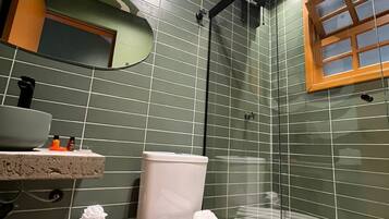 A bathroom with a camouflage-patterned wall, a toilet, a sink, a mirror, and a shower area.