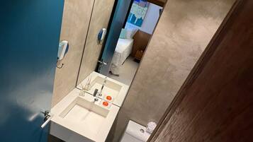 Un baño moderno con lavamanos, espejo y retrete.