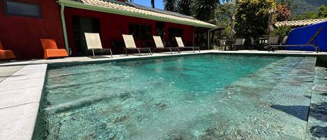 Alberca al aire libre, sombrillas en la alberca y camastros