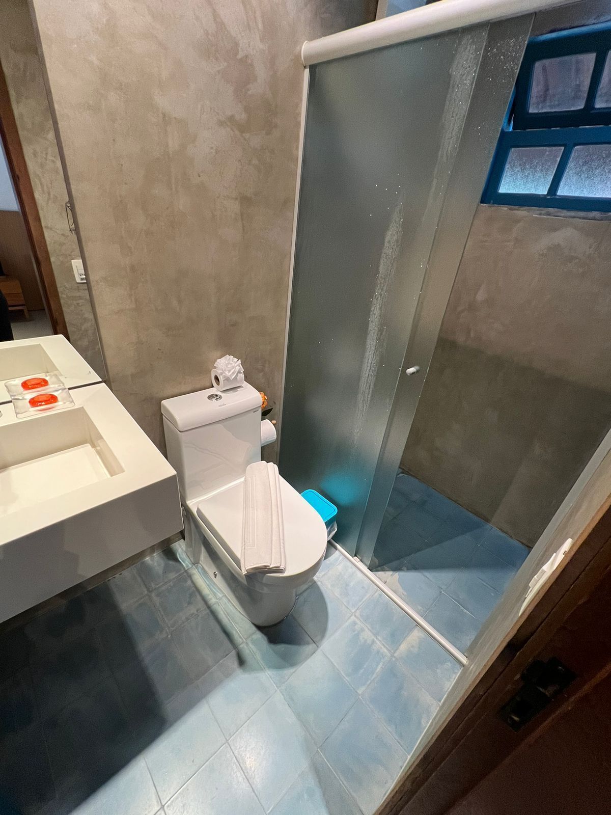 A modern bathroom with a toilet, a glass shower enclosure, and a white sink.