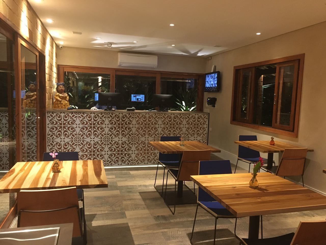 Un restaurante con mesas y sillas de madera, un muro decorativo y un televisor montado en la pared.