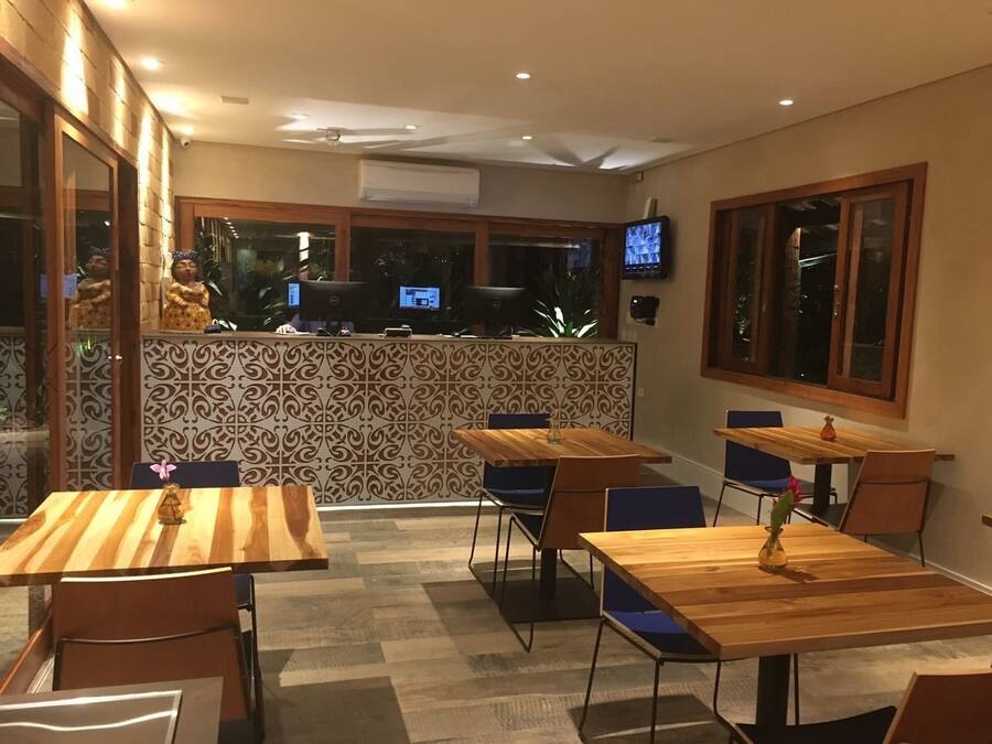 Un restaurante con mesas y sillas de madera, un muro decorativo y un televisor montado en la pared.
