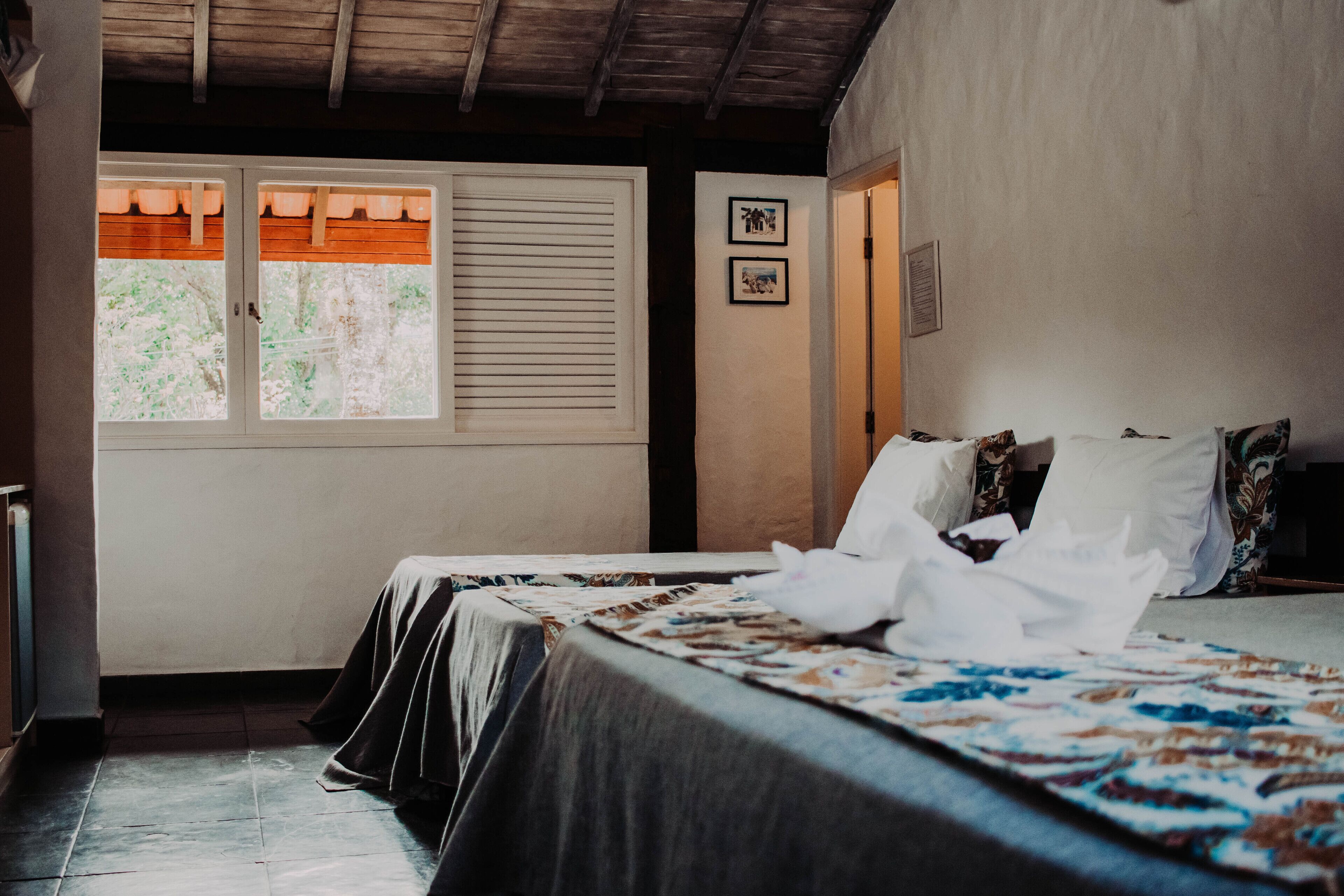 Un dormitorio con dos camas, una ventana con persianas y una puerta.