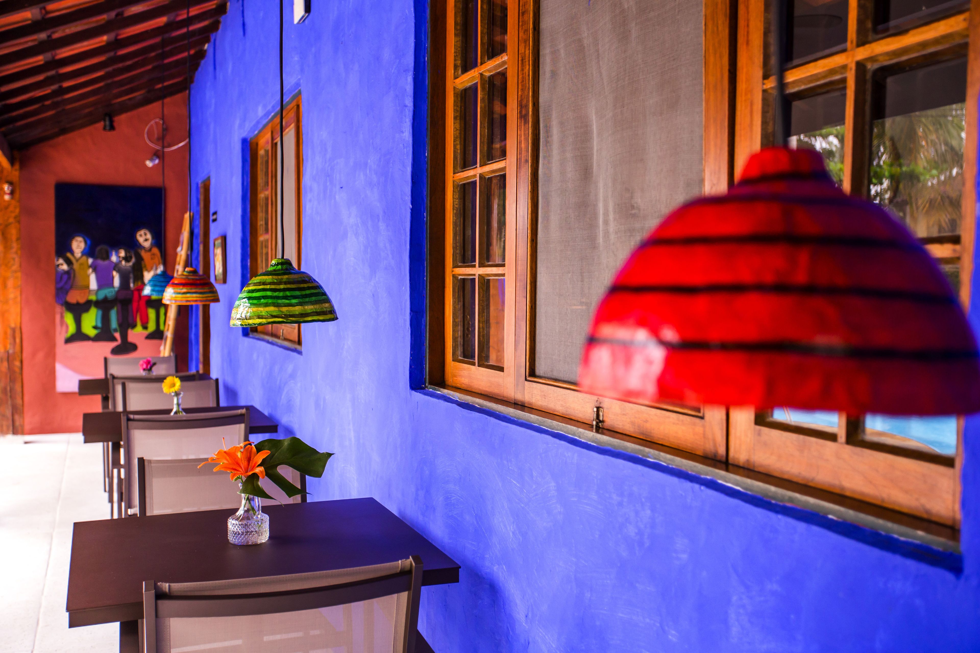 Un edificio azul con ventanas de madera y una mesa con un jarrón de flores.