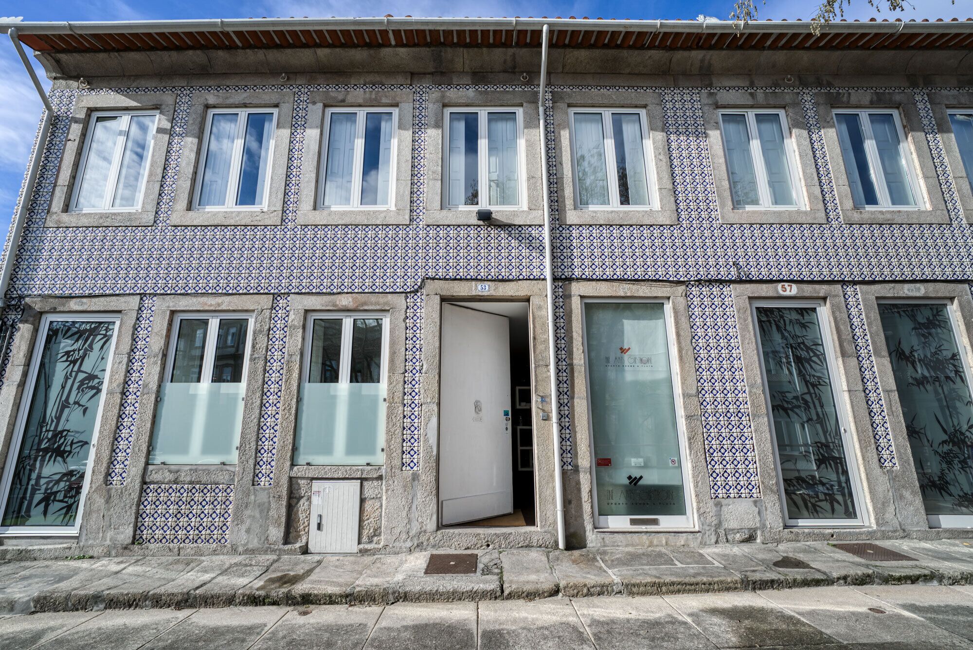 A building with a tiled facade, multiple windows, and a door.