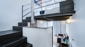 A modern interior with a staircase, a sofa, and a small table with bottles. - Olala Fine Arts Studios (Porto)
