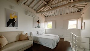 A room with a wooden ceiling, a sofa, two beds, a window, and artwork on the walls. - Olala Fine Arts Studios (Porto)