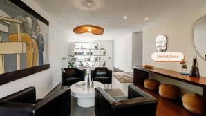 A modern living room with a round coffee table, black leather sofas, a bookshelf, and a large painting on the wall. - Olala Fine Arts Studios (Porto)