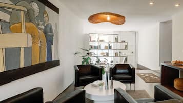 Una sala de estar moderna con una mesa redonda, sofás de cuero negro, una estantería y un cuadro grande en la pared.